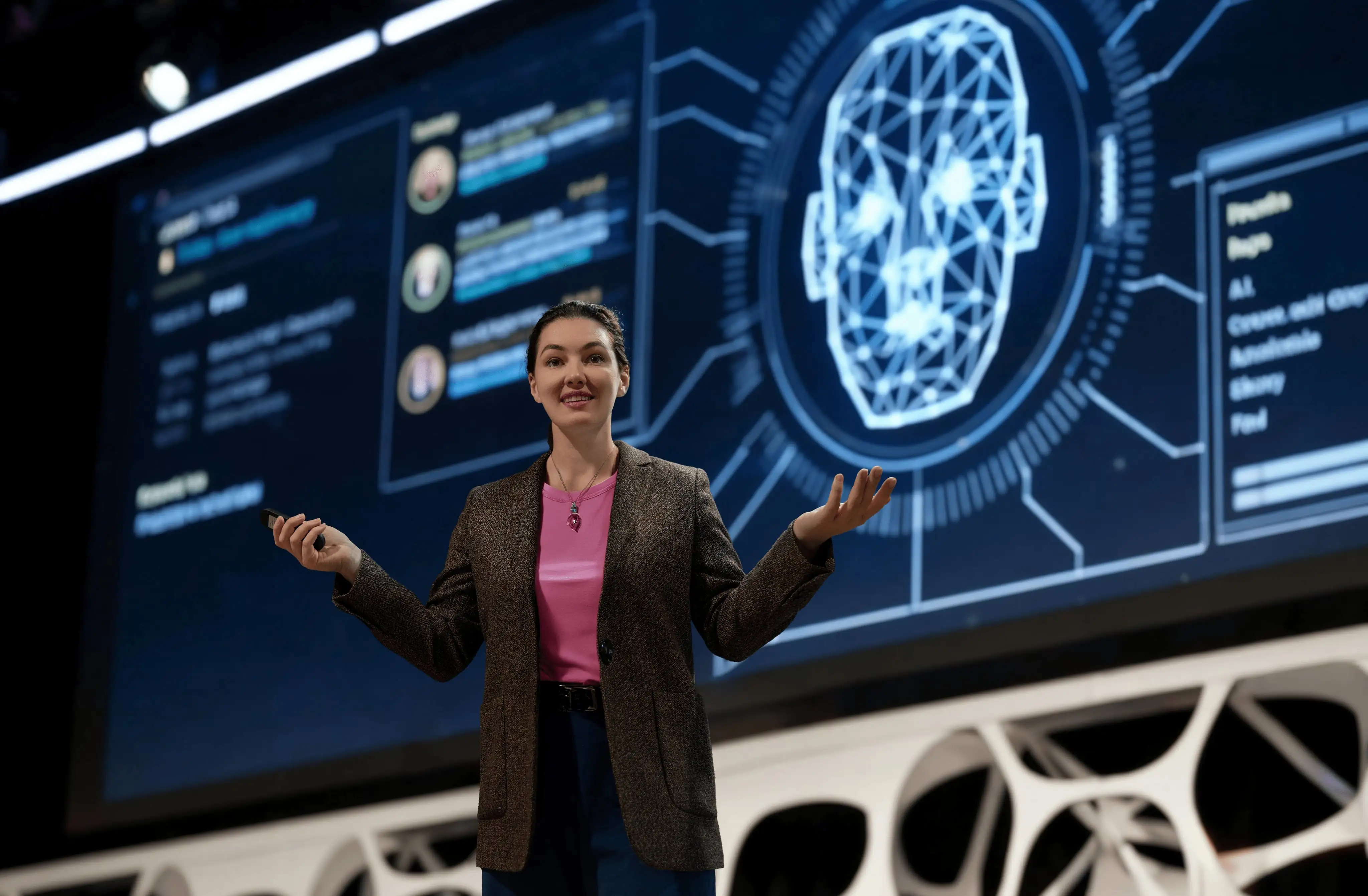 A speaker stands on stage presenting in front of a large screen featuring a digital brain graphic and AI-themed data.