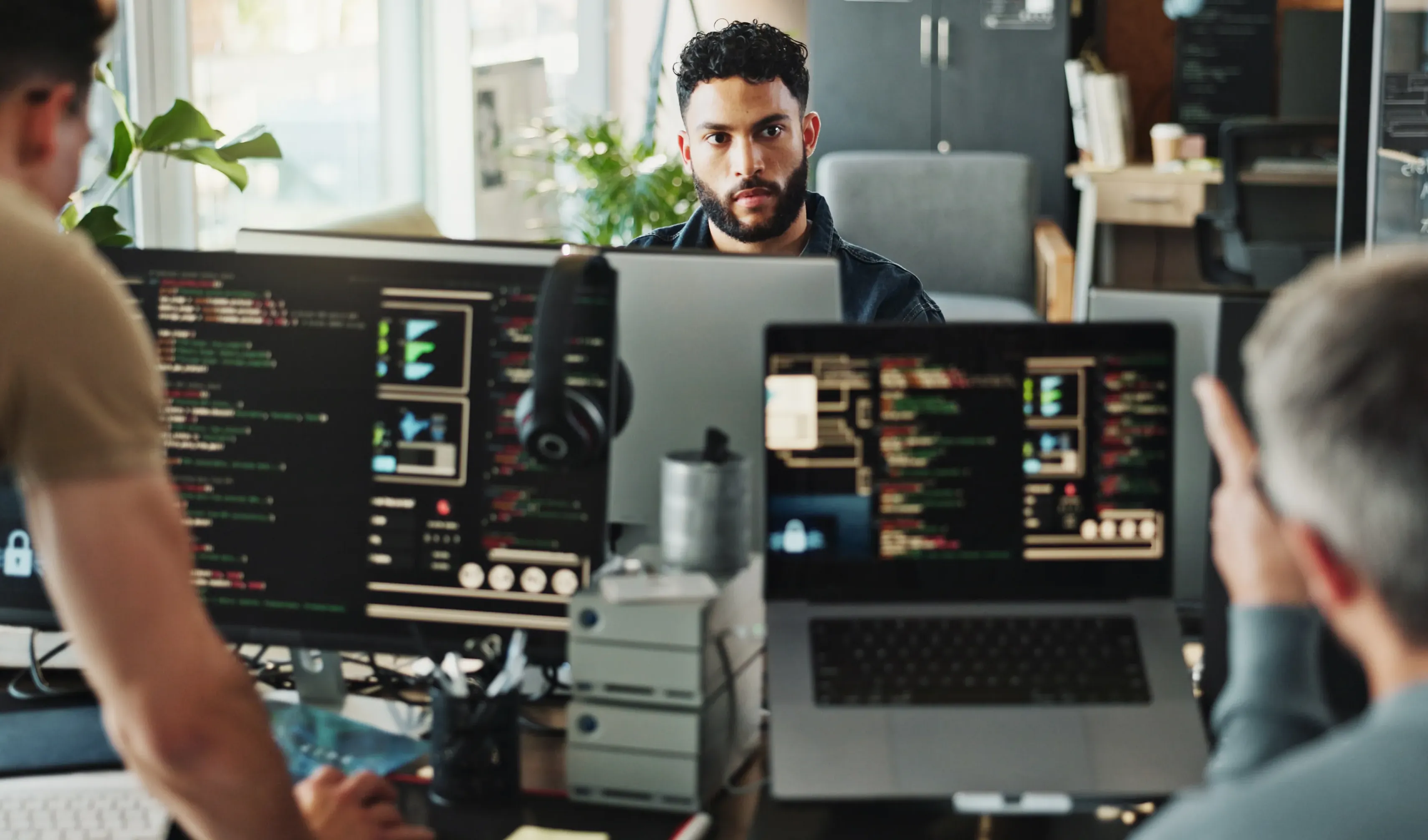 Two people explaining to a third person using their screens with code.