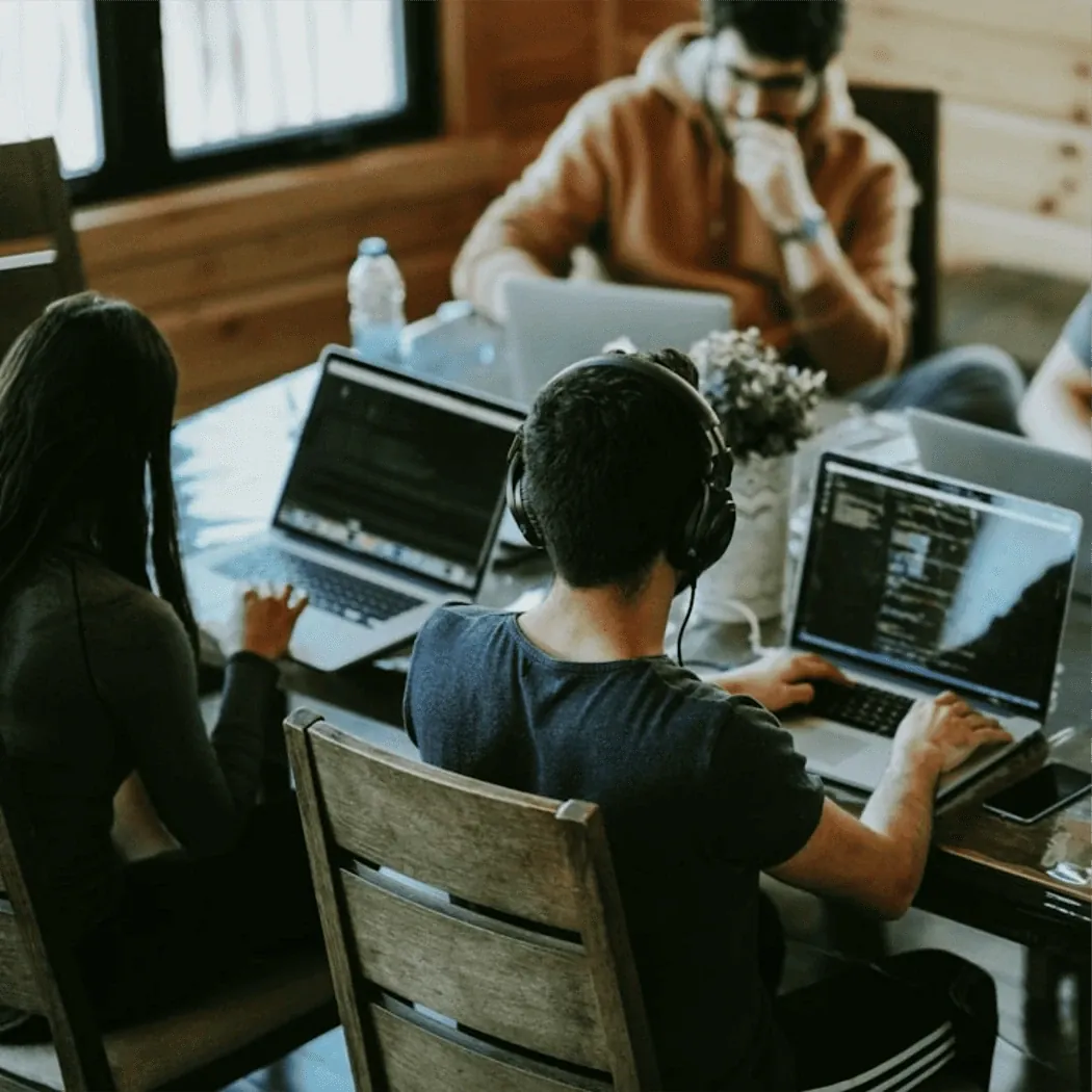 Three people working on their laptops at the same table.