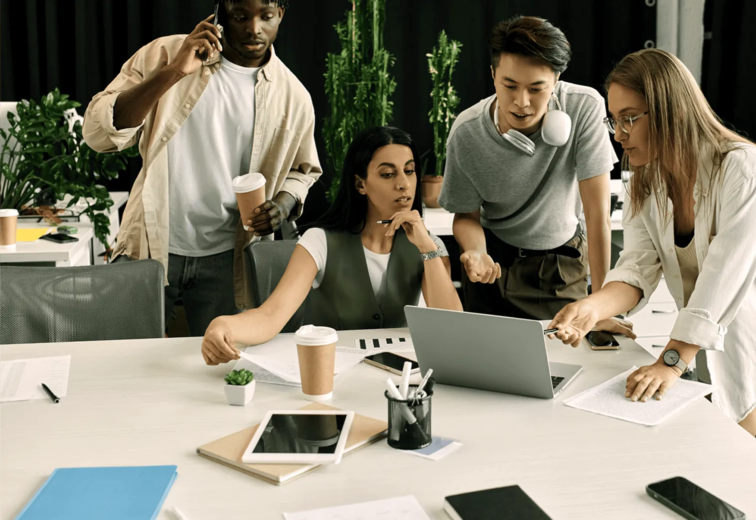 Four people looking at a laptop on a white table.